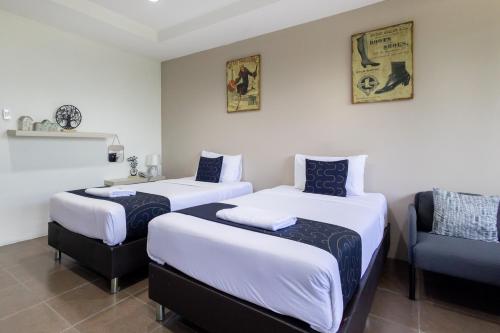 a room with two beds and a chair in it at Nature Boutique Residence in Bangkok