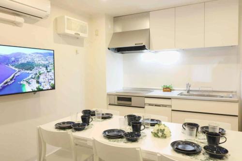 a kitchen with a table with chairs and a tv at Shin Osaka Grand Heights SG51 in Osaka