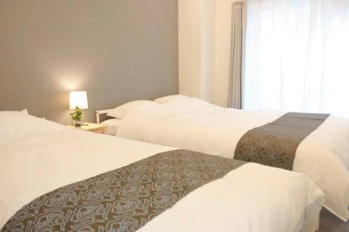 a hotel room with two beds and a window at Shin Osaka Grand Heights SG51 in Osaka