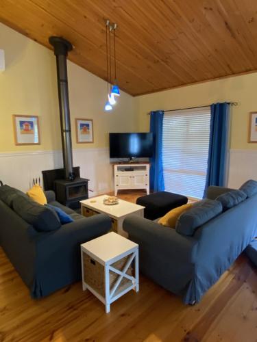 a living room with two couches and a stove at Banksia Views in Sandy Point