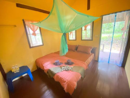 a bedroom with two beds with a canopy above them at Eco Bungalow in Ko Phayam