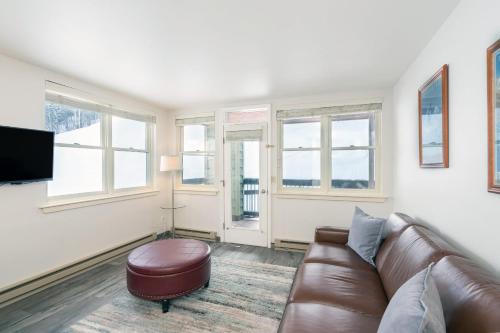 a living room with a brown leather couch and windows at Etta Place 1 by AvantStay Ski In Ski Out Unit w Views of the Slopes in Telluride