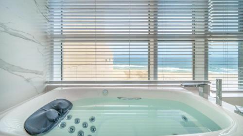 a bath tub in a bathroom with a window at Goseong Moneblue Pension in Goseong