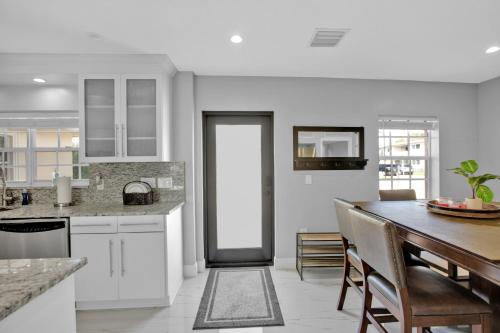 a kitchen with white cabinets and a table with chairs at Luxury Water Front, Heated Pool & Jacuzzi, 5bdrm in Pompano Beach