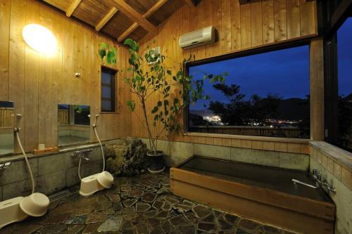 a bathroom with a bath tub and a window at 山魚亭 in Izunokuni