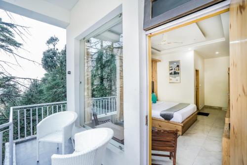 a room with a balcony with a bed and chairs at The Bunksters Mcleodganj, Dharmkot in McLeod Ganj