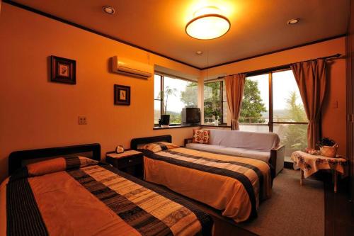 a bedroom with two beds and a couch and a window at 山魚亭 in Izunokuni