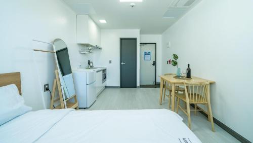 a bedroom with a bed and a table and a kitchen at Yeosu Nangmanstay pension in Yeosu