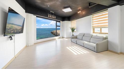 a living room with a couch and a large window at Goseong Leumeleu63 Pension in Goseong