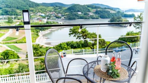 a table on a balcony with a view of the water at Yeosu Sky Pension in Yeosu