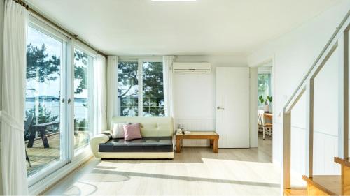 a living room with a couch and windows at Yeosu Sky Pension in Yeosu