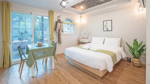 a bedroom with a bed and a desk and a window at Gyeongju Papaya Aegyeondongban Pension in Gyeongju