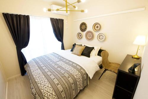 a bedroom with a bed and a desk and a window at Li Kotohogi 302 in Naha