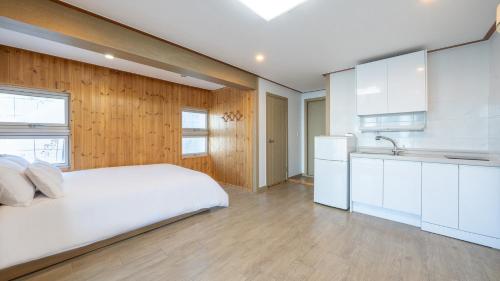 a bedroom with a white bed and a kitchen at Samcheok jangho sanho Pension in Samcheok