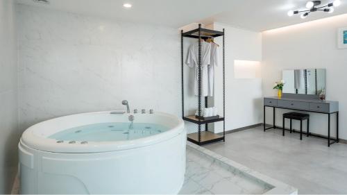 a white bathroom with a tub in a room at Ganghwado Lafamilia Pension in Incheon