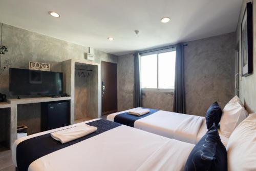 a hotel room with two beds and a television at Nature Boutique Residence in Bangkok