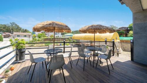 two tables and chairs with umbrellas on a deck at Samcheok Lamer Pension in Samcheok
