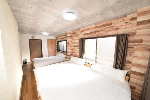 two beds in a room with wooden walls at ACTResidence第二 4室1バスルーム1シャワー3トイレ in Tokyo