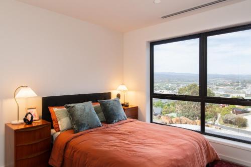 Un dormitorio con una cama y una ventana grande. en Tamar Views, en Inveresk