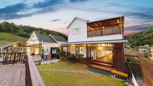 a house with a balcony and a wooden deck at Gapyeong Etoile Pension in Gapyeong