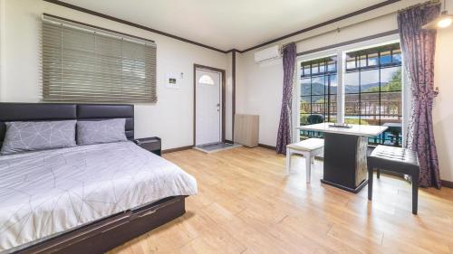 a bedroom with a bed and a desk and windows at Gapyeong Etoile Pension in Gapyeong