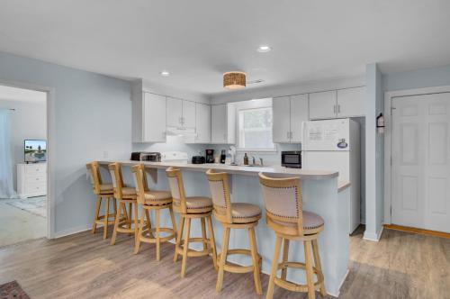 a kitchen with white cabinets and a bar with stools at Ion by AvantStay Walk to Beach Dining Shopping Central Location Deck in Sullivans Island