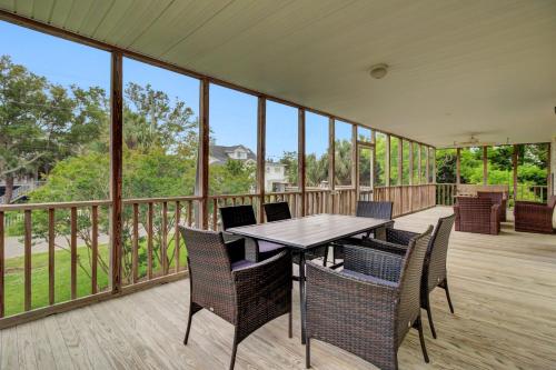 a screened porch with a wooden table and chairs at Ion by AvantStay Walk to Beach Dining Shopping Central Location Deck in Sullivans Island