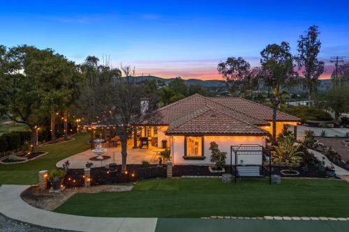a house with lights in the yard at dusk at Breathtaking Meadows by AvantStay Temecula Group Retreat Pool Pickleball Firepit Hot Tub in Temecula