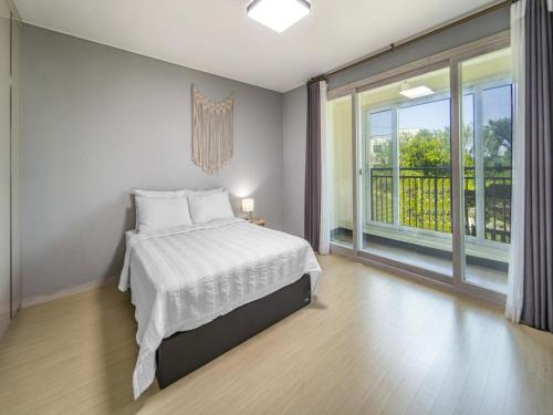 a bedroom with a bed and a large window at Jeju Timberhouse Pension in Jeju