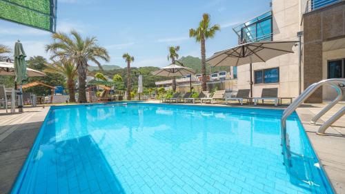 una grande piscina blu con due ombrelloni di Geoje Break Time Pension a Geoje