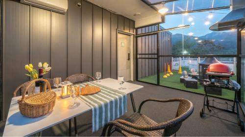 una sala da pranzo con tavolo, sedie e griglia di Gapyeong Dangdangi Pet Poolvilla Blue a Gapyeong