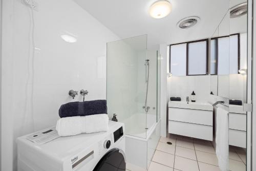 ポート・マッコリーにある6 58 Pacific Drive - Beachfront modern apartmentの洗面台と洗濯機を備えた白いバスルーム