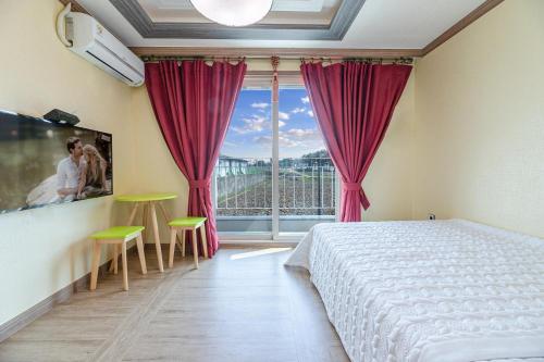 a bedroom with a bed and a large window at Gyeongju Gamposole Pension in Gyeongju