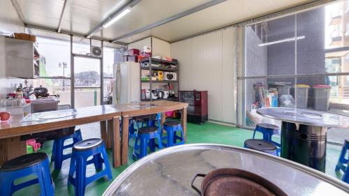a kitchen with tables and stools in a room at Gyeongju Gamposole Pension in Gyeongju