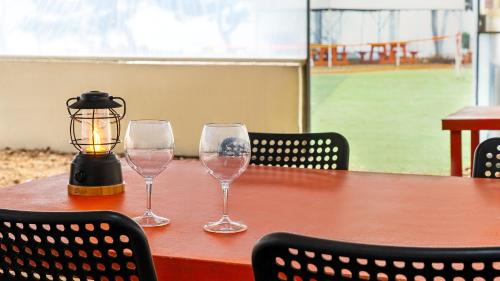 two wine glasses sitting on a table with a lantern at Daebudo green beach Pension in Ansan