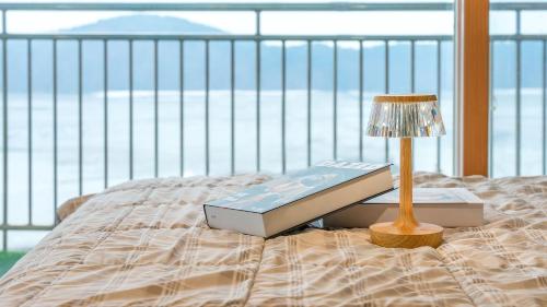 a bed with a lamp and a book on it at Daebudo green beach Pension in Ansan