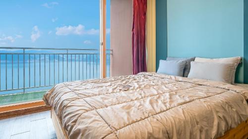 een slaapkamer met een bed en een groot raam bij Daebudo green beach Pension in Ansan
