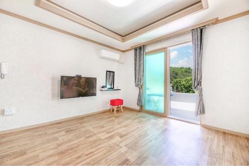 an empty living room with a red chair and a large window at Samcheok Greenhyang Pension in Samcheok