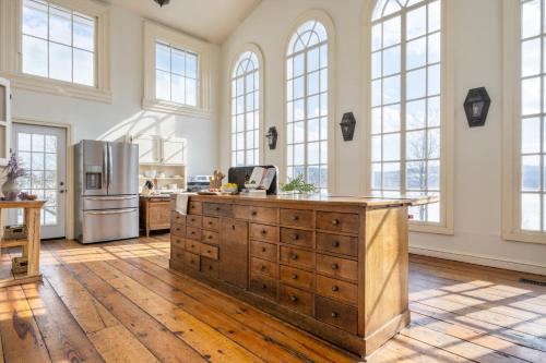 a kitchen with a wooden island in a room with windows at River House by AvantStay Historic Secluded Estate on the Hudson River w Pool Sleeps 24 in Hudson