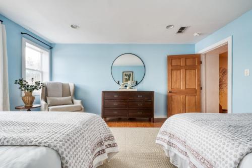 a blue bedroom with two beds and a mirror at River House by AvantStay Historic Secluded Estate on the Hudson River w Pool Sleeps 24 in Hudson