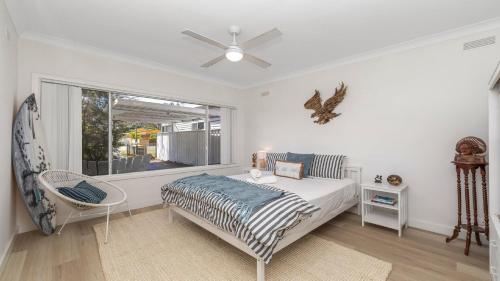 Un dormitorio con una cama y una silla y una ventana. en Sunshine Shack - Umina Beach, en Umina Beach 