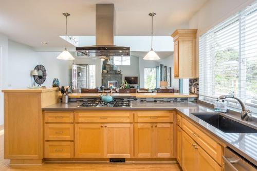 a kitchen with wooden cabinets and a sink at Villa Manzanita by AvantStay Hot Tub 1 Block to BeachTown Chefs Kitchen in Manzanita