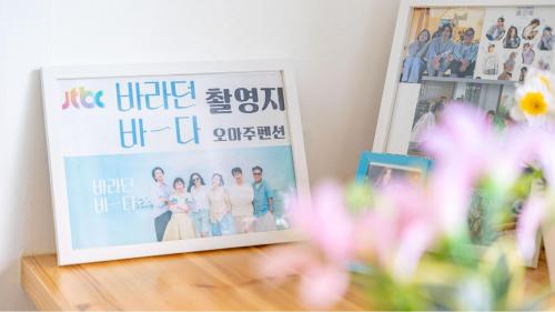 a picture in a frame on a table with flowers at Goseong Omaju Pension in Goseong
