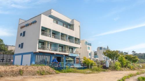 a white building on the side of a dirt road at Jebudo Gloria Pension in Hwaseong