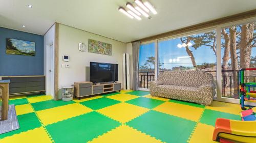 a living room with a couch and a television at Goseong Pinetree Pension in Goseong