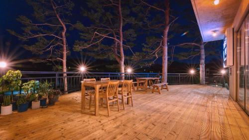 a wooden deck with tables and chairs at night at Goseong Pinetree Pension in Goseong