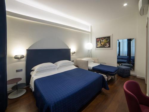 レッジョ・ディ・カラブリアにあるTown House Morganaの青いベッドと椅子が備わるホテルルームです。