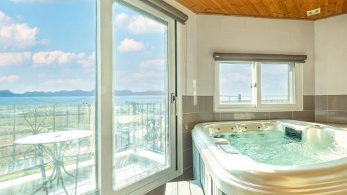 eine Badewanne in einem Raum mit einem großen Fenster in der Unterkunft Ganghwa Hanabi Pension in Incheon