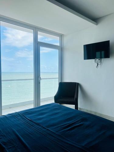 a bedroom with a bed and a chair and a window at Vista a Playa con Alberca en Blvd principal frente al Mar 3hab in Boca del Río