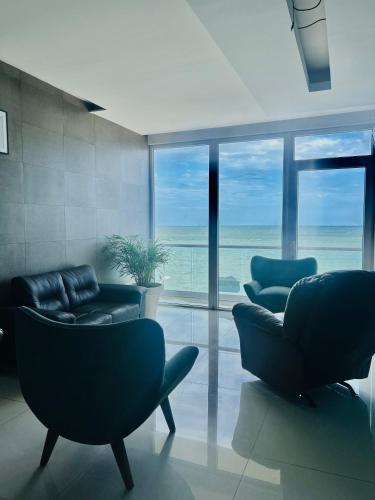 a living room with chairs and a view of the ocean at Vista a Playa con Alberca en Blvd principal frente al Mar 3hab in Boca del Río